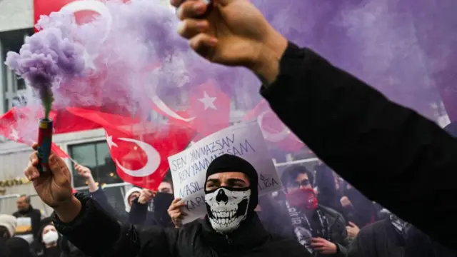 Para pengunjuk rasa memegang suar asap dalam demonstrasi di balai kota Istanbul, Turki, pada 24 Maret 2025.