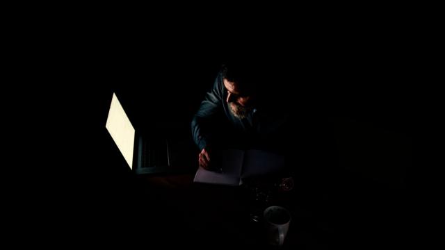 homem escreve em computador no escuro