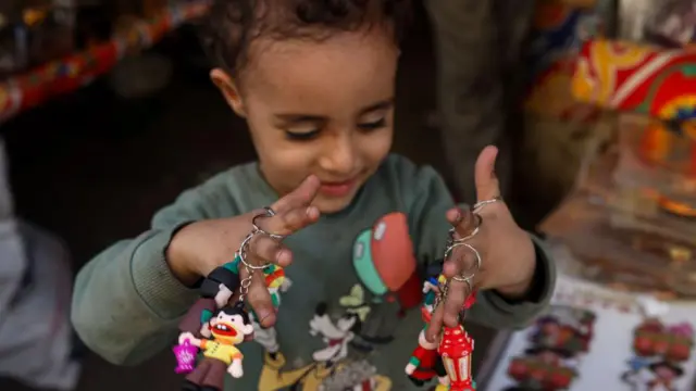 طفلة صغيرة تحمل عدد من الميداليات بكلتا يديها.