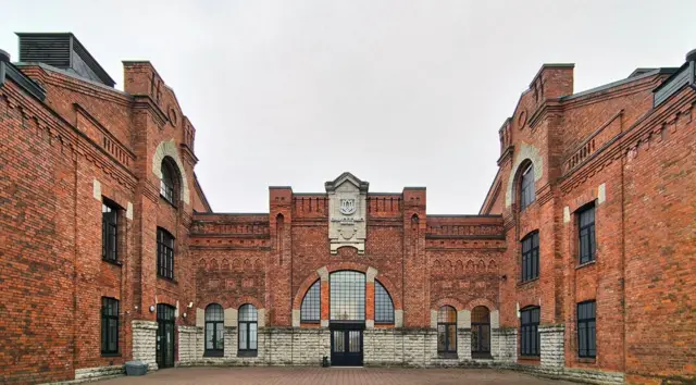 Казармы из красного кирпича, пустынный вымощенный двор
