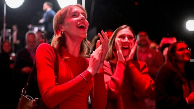 Liberal Partili kırmızı giymiş kadınlar, gülerek ve tezahurat yaparak seçim zaferini kutluyor.