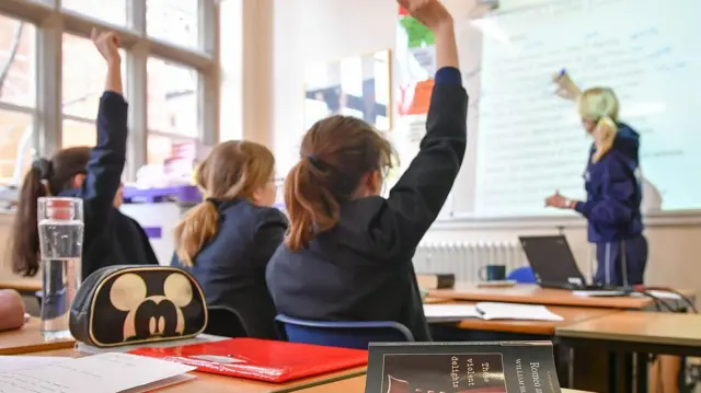 学生们举手发言,教师在白板上书写。