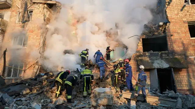 آتش‌نشانان شعله‌ها را در یک ساختمان مسکونی خاموش می‌کنند، در حالی که نیروهای امدادی پس از حمله موشک بالستیک روسیه به کی‌یف در اوکراین، میان آوار دنبال قربانیان می‌گردند
