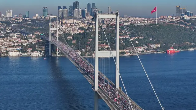 نمایی از استانبول با پل بزرگ موتر رو بر روی دریا و پس زمینه شهر. یک پرچم بزرگ ترکیه بر فراز تپه‌ای در گوشه سمت راست دیده می‌شود