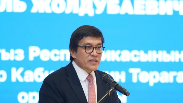 Эдиль Байсалов, мужчина в очках в темном костюме и розовом галстуке выступает с трибуны