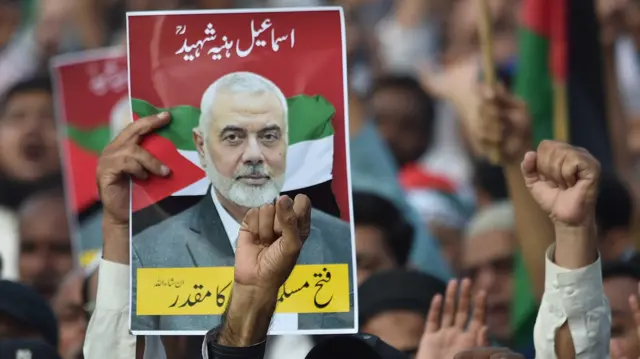 A poster showing Ismail Haniyeh is held up by protesters