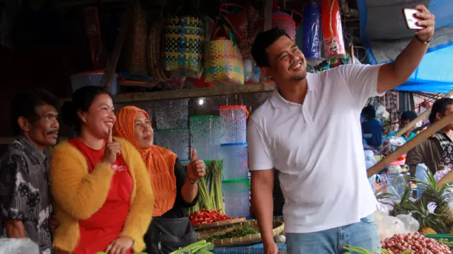 Calon Gubernur Sumatra Utara Bobby Nasution (kanan) berfoto bersama pedagang saat kampanye di Pusat Pasar Kaban Jahe, Kabupaten Karo, Sumatera Utara, Sabtu (12/10).