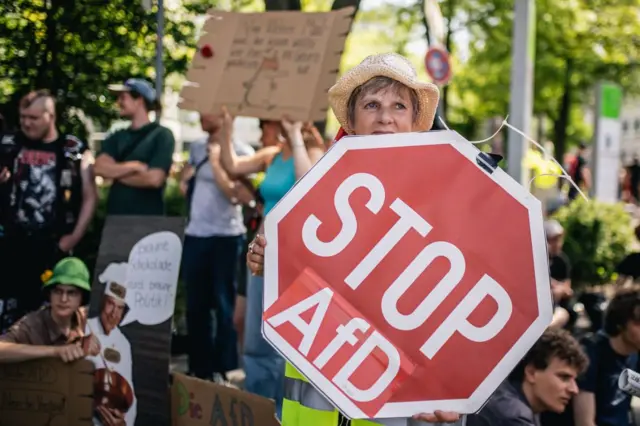 Mulher carrega cartazjogo de ganhar dinheiro pixprotesto contra o partido AfD