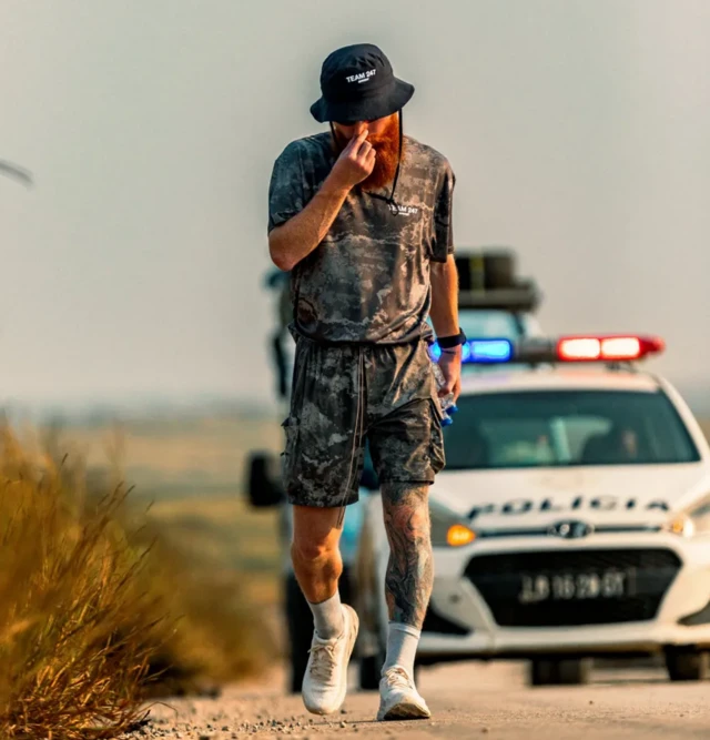 Ruus Cook marchant devant une voiture de police