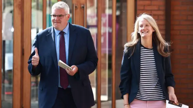 Onyeisi ndọrọndọrọ ọchịchị Democratic Unionist Party (DUP) bụ Gavin Robinson a tụọla vootu na Belfast. Na photo a nwunye na nọ ya na akụkụ.