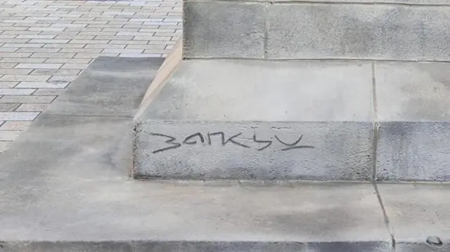 نام بنکسی در پایین مجسمه