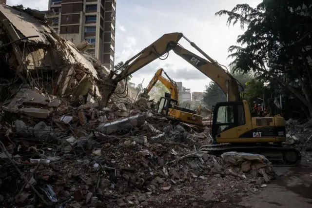 Bulldóceres amarillos trabajando junto a los escombros de un edificio en Caracas.