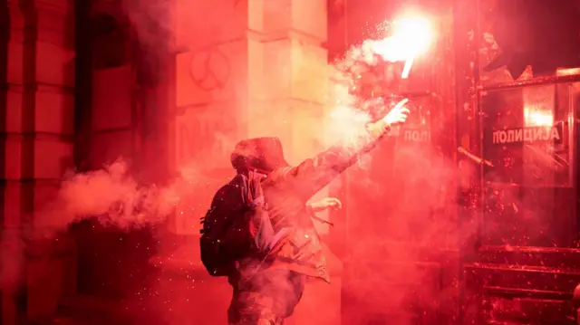 Участник столкновений с полицией бросает фальшфейер. Нови-Сад, ноябрь 2024