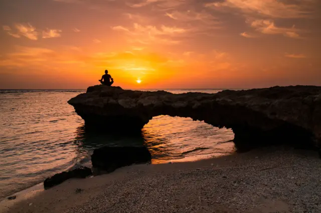 හිරු බැස යන වෙරළ තීරයක යෝග ව්යායාම කරන පිරිමියෙක් (Man silhouette)