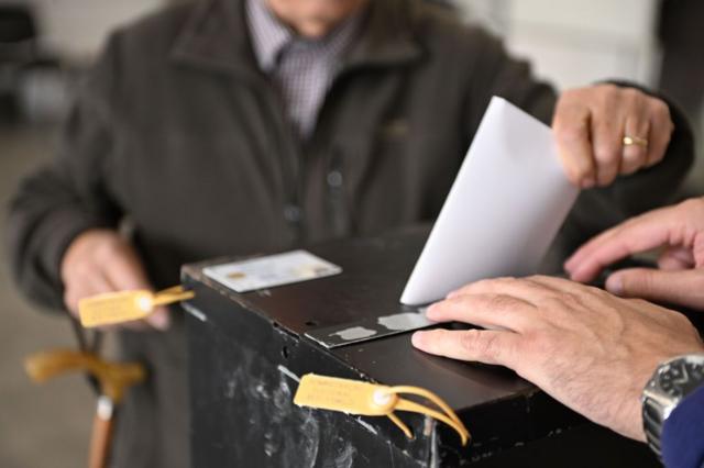Pessoa depositando voto de papel em urna
