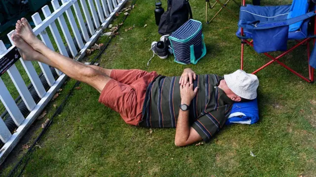 Homem descansando com pés apoiados em cerca