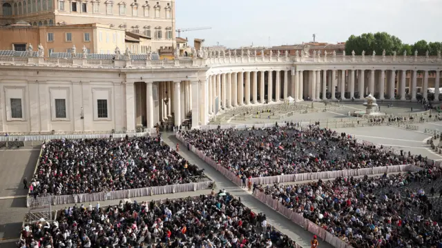 صورة تظهر حشوداً من الناس في ساحة القديس بطرس في انتظار وصول جثمان البابا إلى الكاتدرائية.