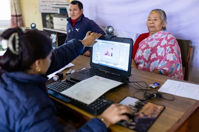 मतदाता परिचयपत्रका लागि फोटो खिचाउँदै एक वृद्धा