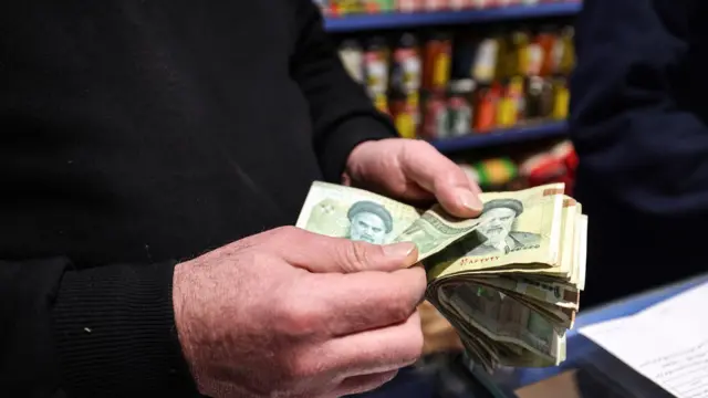في السابع من يناير/كانون الثاني 2026، قام صاحب متجر في العاصمة طهران بعدّ الأوراق النقدية الإيرانية. وقد تضرر الاقتصاد الإيراني بشدة جراء العقوبات الدولية القاسية، حيث فقدت العملة الوطنية، الريال، أكثر من ثلث قيمتها مقابل الدولار الأمريكي خلال العام الماضي، وبلغ التضخم أرقاماً مزدوجة