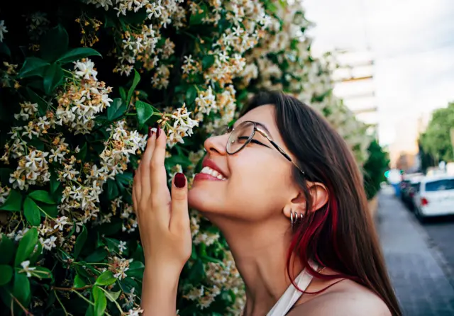 फूलों की महक लेती महिला