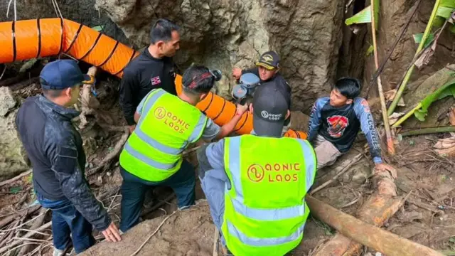Rescuers trying to fix an orange pump onto one of the cave's entrances