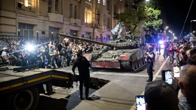 Tanque passando no meio de uma rua, com pessoas aglomeradas em ambos os lados da calçada, em Rostov-on-Don, em 24 de junho de 2023.