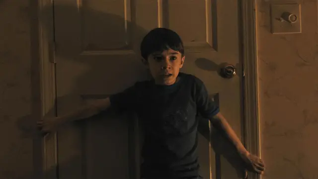 Кадр із фільму - хлопчик у темній футболці затуляє собою двері 