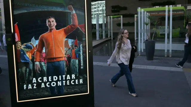 Propaganda de site de apostas em painel em rua de São Paulo, com transeunte passando ao fundo