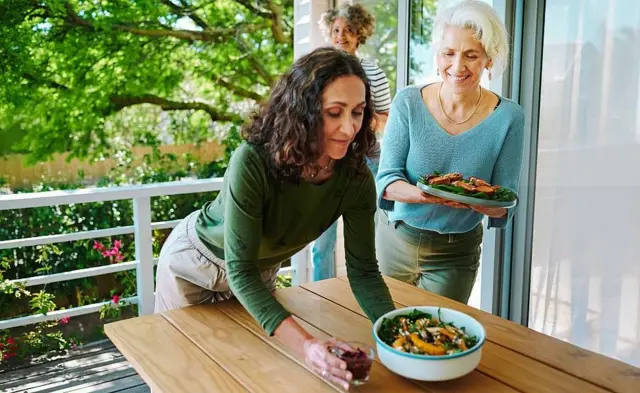 Mujeres colocando fuentes con comida en una mesa