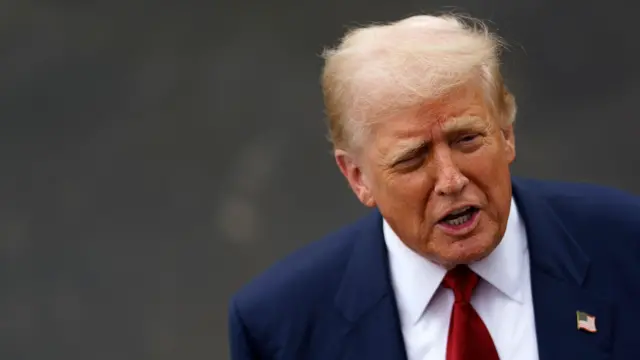 O presidente americano Donald Trump, de terno azul e gravata vermelha