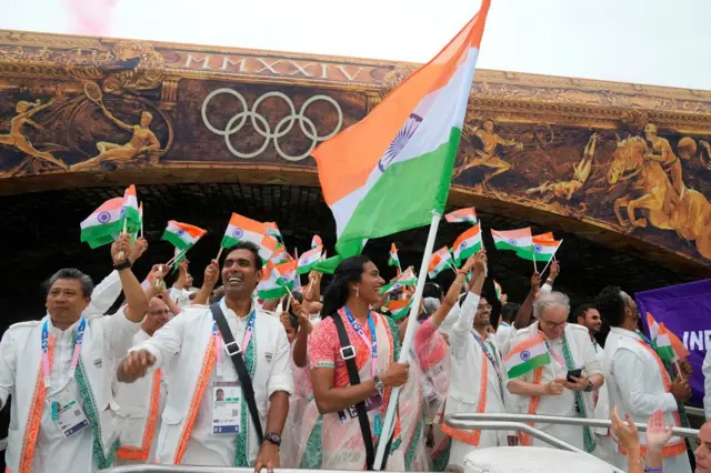 Les athlètes indiens agitent leurs drapeaux nationaux depuis un bateau sur la Seine lors de la cérémonie d'ouverture des Jeux olympiques d'été de 2024.