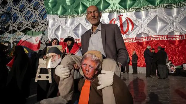 Seorang pria tua Iran tampil dengan patung Presiden AS Donald Trump, sementara wanita berjilbab memegang potret Pemimpin Tertinggi Iran, Ayatollah Ali Khamenei, selama rapat umum pro-pemerintah di Teheran selatan, Iran, pada 30 Desember 2025