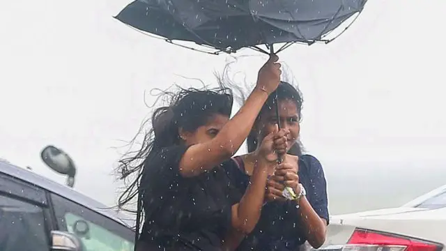 Two young women struggle to hold an umbrella steady as strong winds from Cyclone ''Ditwah'' hit in Colombo, Sri Lanka, on November 28, 2025. (Photo by Krishan Kariyawasam/NurPhoto via Getty Images)