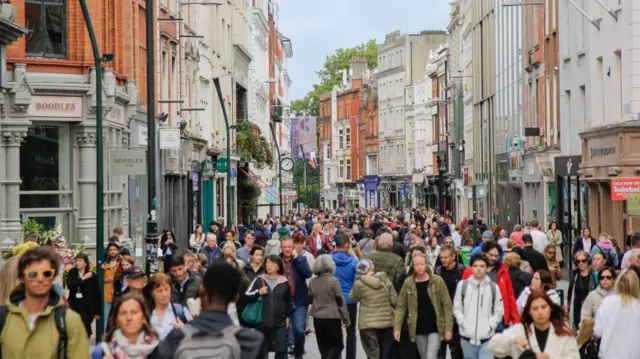 Foto do centro de Dublin com centenas de pessoas na rua. 