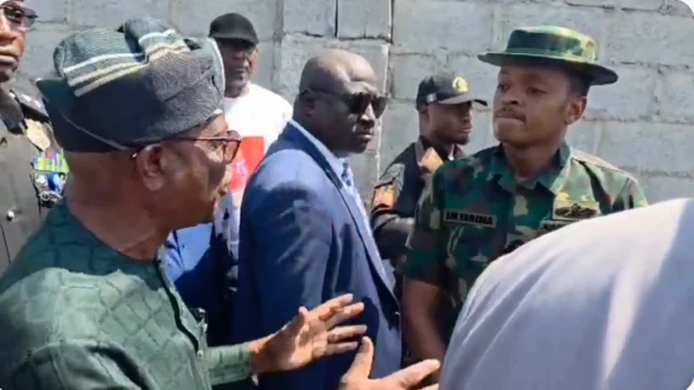 Nyesom Wike ń woju ọmọ ológun to wa ninu aṣọ ológun tí tíì ṣe aláwọ̀ èwe. Ọ̀pọ̀ èèyàn yí àwọn méjèèjì ká.