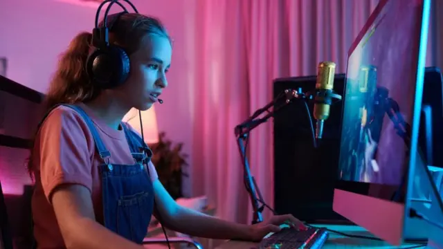 Niña sentada frente a una computadora mirando la pantalla