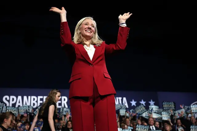 La futura gobernadora de Virginia, Abigail Spanberger, celebra mientras sube al escenario durante su mitin electoral en el Greater Richmond Convention Center. Lleva un traje rojo. 