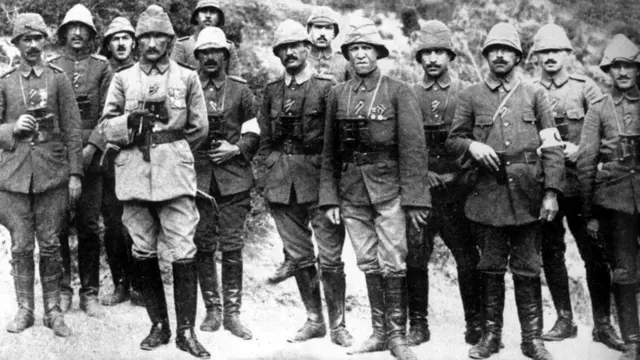 Çanakkale Savaşı sırasında Mustafa Kemal ve arkadaşları cephede yanyana hemen hepsi boynunda asılı dürbün, çizmeler ve dönemin askeri giysileriyle. Siyah beyaz. 