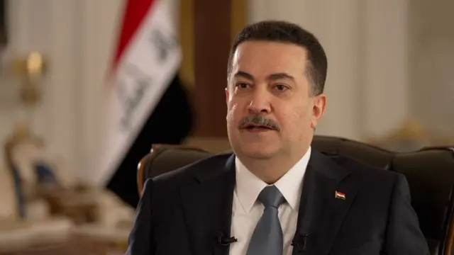 رئيس الوزراء العراقي مرتدياً بدلة سوداء وقميصاً أبيض وربطة عنق رصاصية اللون.