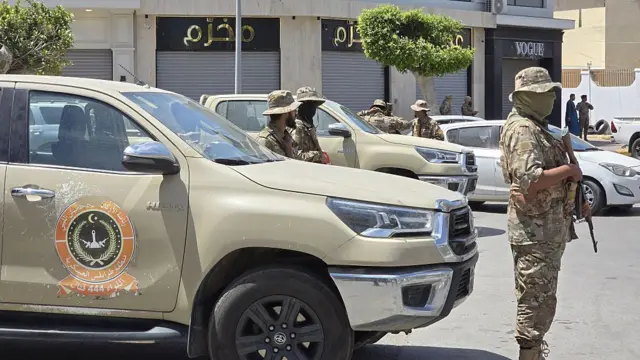 عدد من أفراد العسكر الليبي يحملون أسلحة وخلفهم مركبات تابعة لهم.