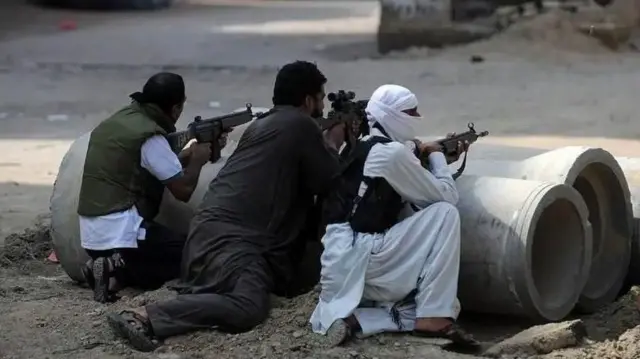 துப்பாக்கியுடன் இருக்கும் மூவர் 