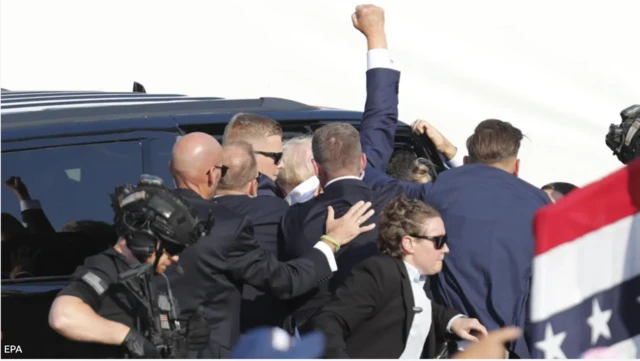 ကားထဲမဝင်ခင် ထောက်ခံသူတွေကို လက်ထောင်ပြနေတဲ့ မစ္စတာထရမ့်