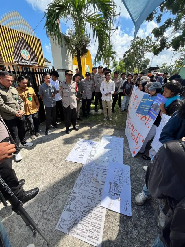 Sekelompok orang sedang menggelar poster yang berisi tuntutan menolak proyek ekowisata di Gunung Rinjani.