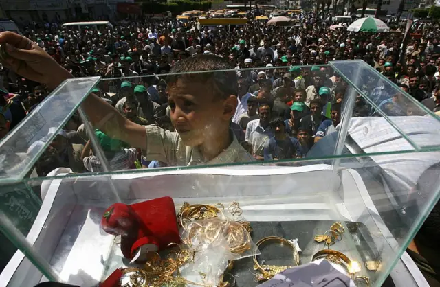 Uma criança palestina e uma urna com dinheiro e joias.