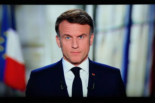 Le président français Emmanuel Macron est vu sur un écran alors qu'il prononce son discours télévisé du Nouvel An à la nation depuis le palais de l'Élysée, à Paris, le 31 décembre 2024.