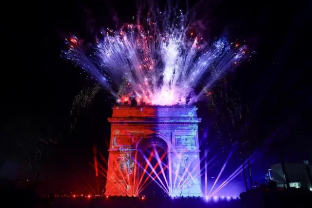 El Arco del Triunfo iluminado en París con fuegos artificiales y luces