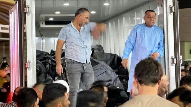 মৃতদেহ ভর্তি ট্রাকের কাছে মানুষের ভিড়।