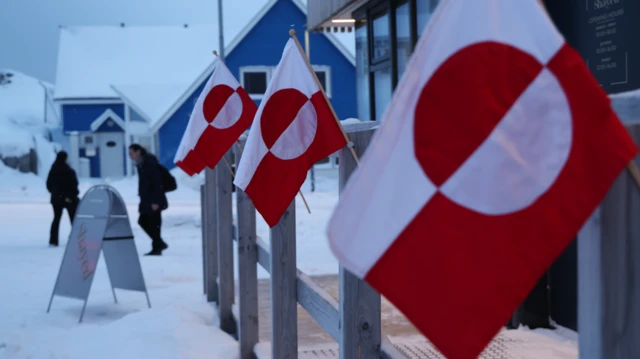  Pipo dey waka past Greenlandic flags outside one shop in di city centre