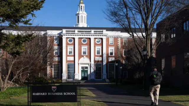 Un hombre camina hacia la entrada al edificio de la Harvard Business School.