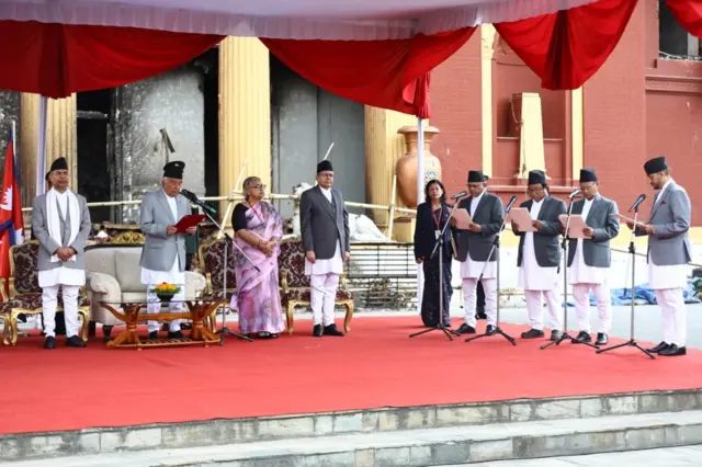 प्रधानमन्त्री, राष्ट्रिय सभाका अध्यक्ष र सभामुखको उपस्थितिमा नवनियुक्त मन्त्रीहरूलाई शपथ ग्रहण गराउँदै राष्ट्रपति पौडेल